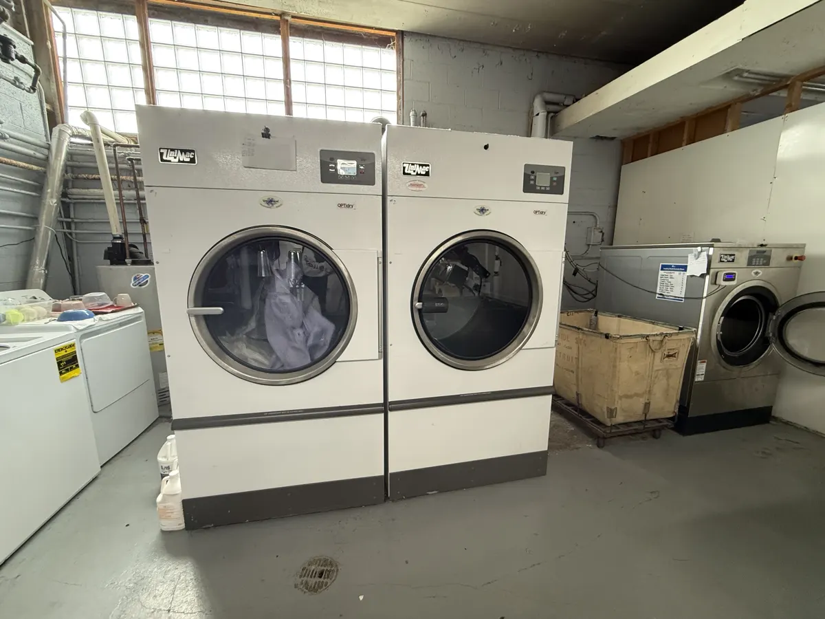 Row of commercial washers and dryers used for cleaning clothes and textiles