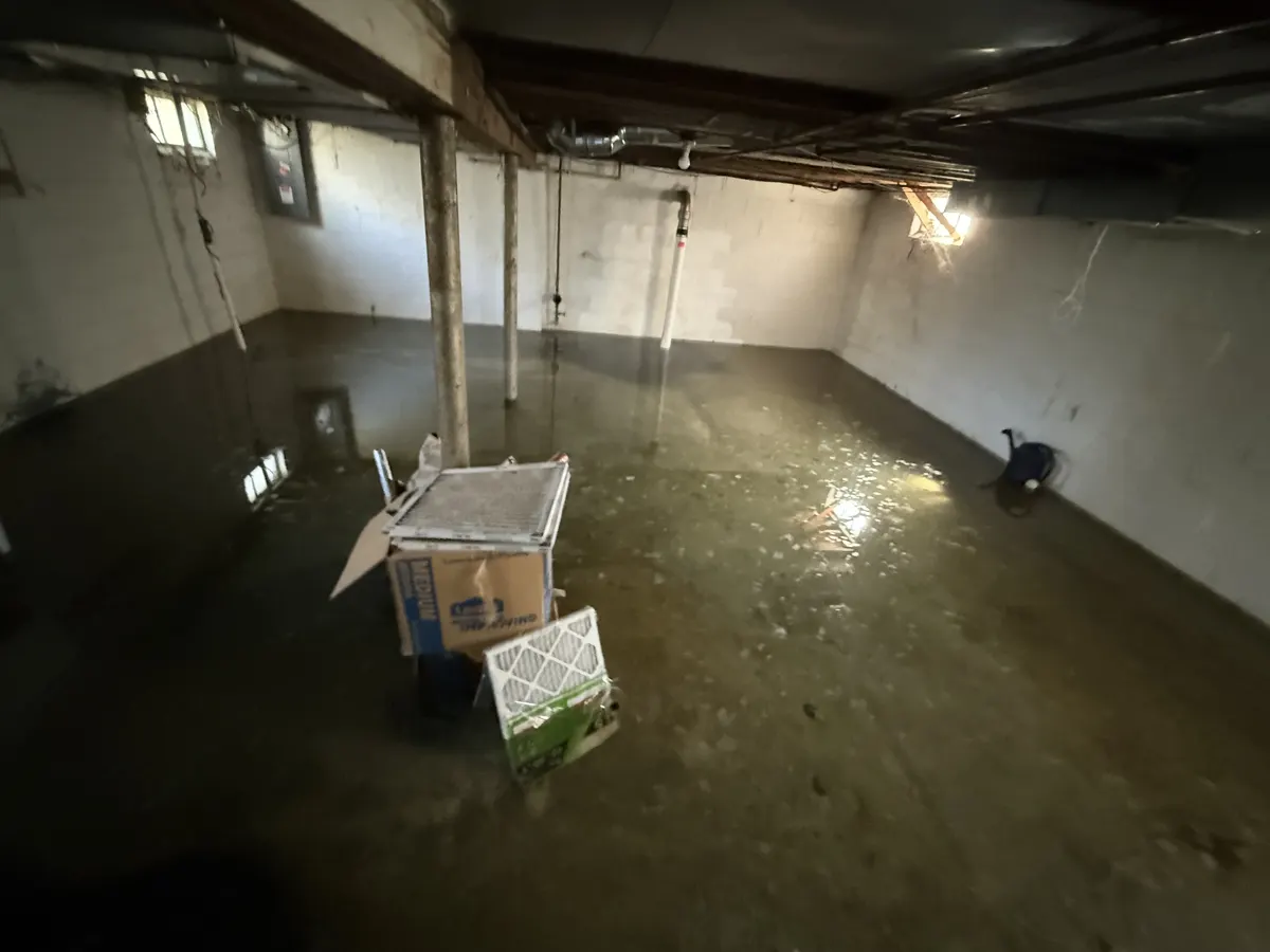 Water on the floor of an unfinished basement with concrete block walls