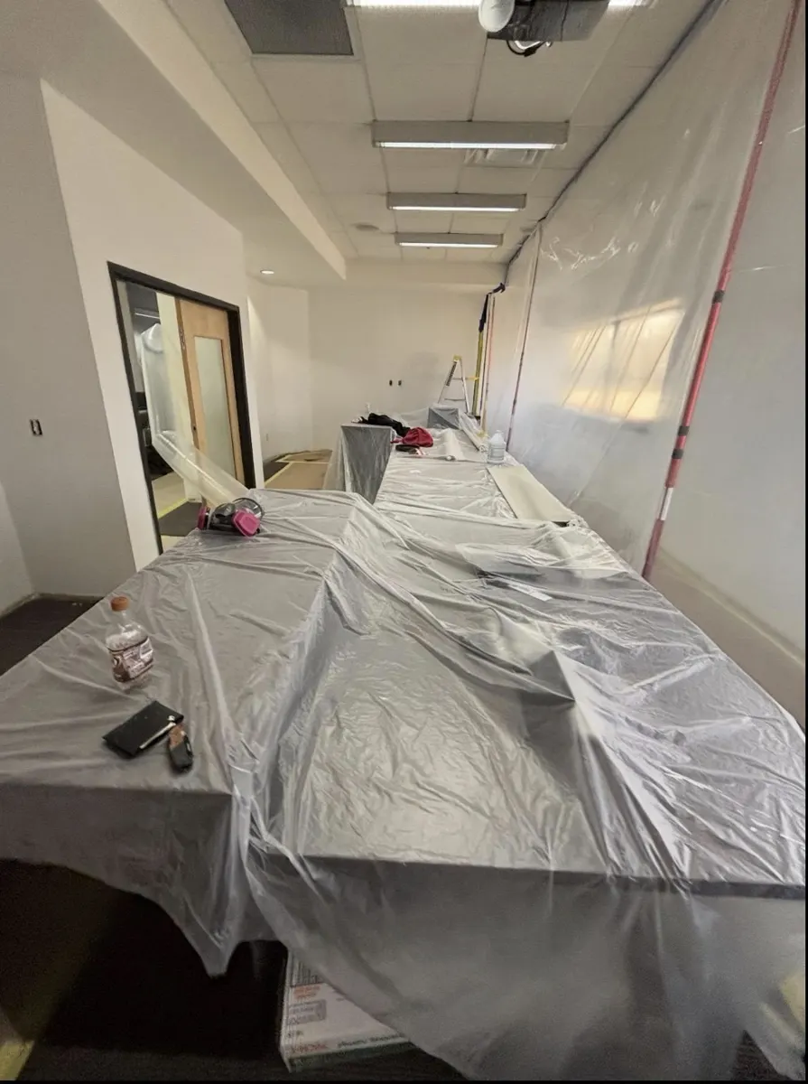 Office room sealed off with plastic sheeting for mold work, with furniture covered